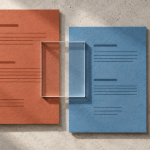 Rust and steel-blue paper record panels overlap a clear rectangular window, with a separate pale panel on a stone surface.